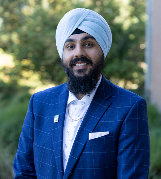 Prince Singh wearing a blue suit and smiling at the camera.