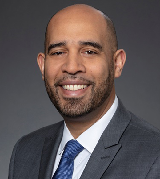 Stephen Abreu wearing a suit and tie. He is smiling.
