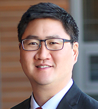 A close-up of a man wearing a suit and glasses.