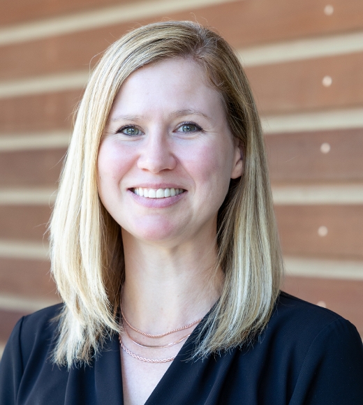 Raelene Dugger, UC Davis Law's Assistant Director of Development, in white. She is softly smiling at the camera.