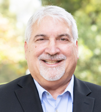 Professor Mark Rigau smiling brightly outside of King Hall.
