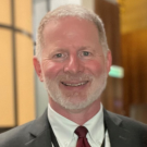 Charles "Dom" Ayotte, Associate Director of Career Services, wearing a suit and smiling.